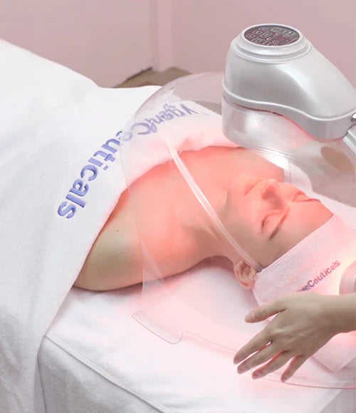 A person lying down receiving a facial oxygen treatment, with a machine above their face.