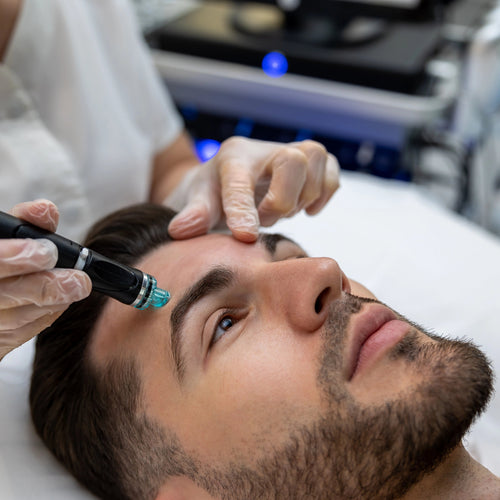 Man receiving a facial treatment with a device from a professional in a clinical setting.