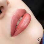 Close-up of a person's lips after a lip blushing makeup treatment, with a natural pink color.