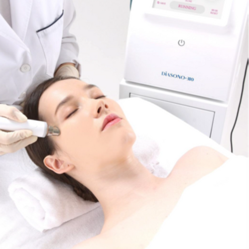 Woman receiving a facial treatment with a machine labeled 'Diasono' in a clinical setting.