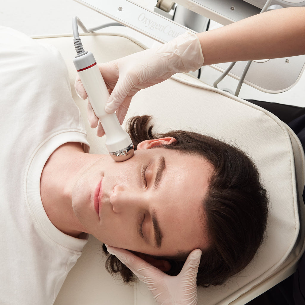 Person receiving a facial treatment with medical equipment on a white background