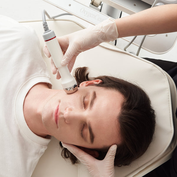 Person receiving a facial treatment with medical equipment on a white background