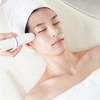 Person receiving a facial treatment with a handheld device on a white background