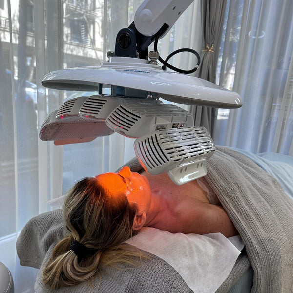 Person receiving LED light therapy treatment with a device above them.