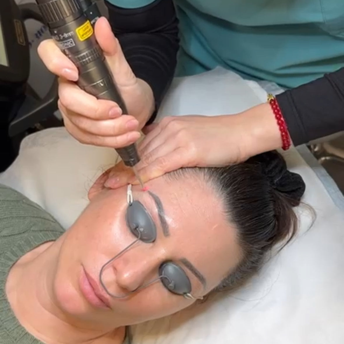 Person receiving a facial treatment with a device on a white background