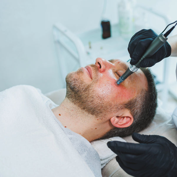 Person receiving a facial treatment with a device from a professional in a clinical setting.