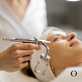 Person receiving a facial treatment with an airbrush device.