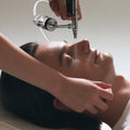 Person receiving a facial treatment with a machine on a white background