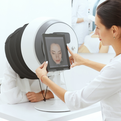 Woman using a digital device to check her face in a mirror with a white background